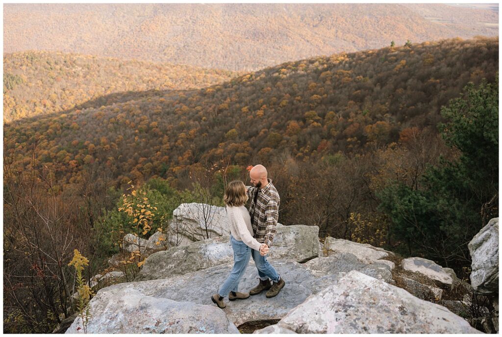 Couple standing on rock with trees and valley in the background