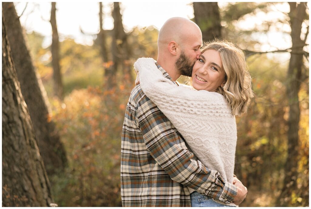 Woman smiling at camera while man kisses her cheek