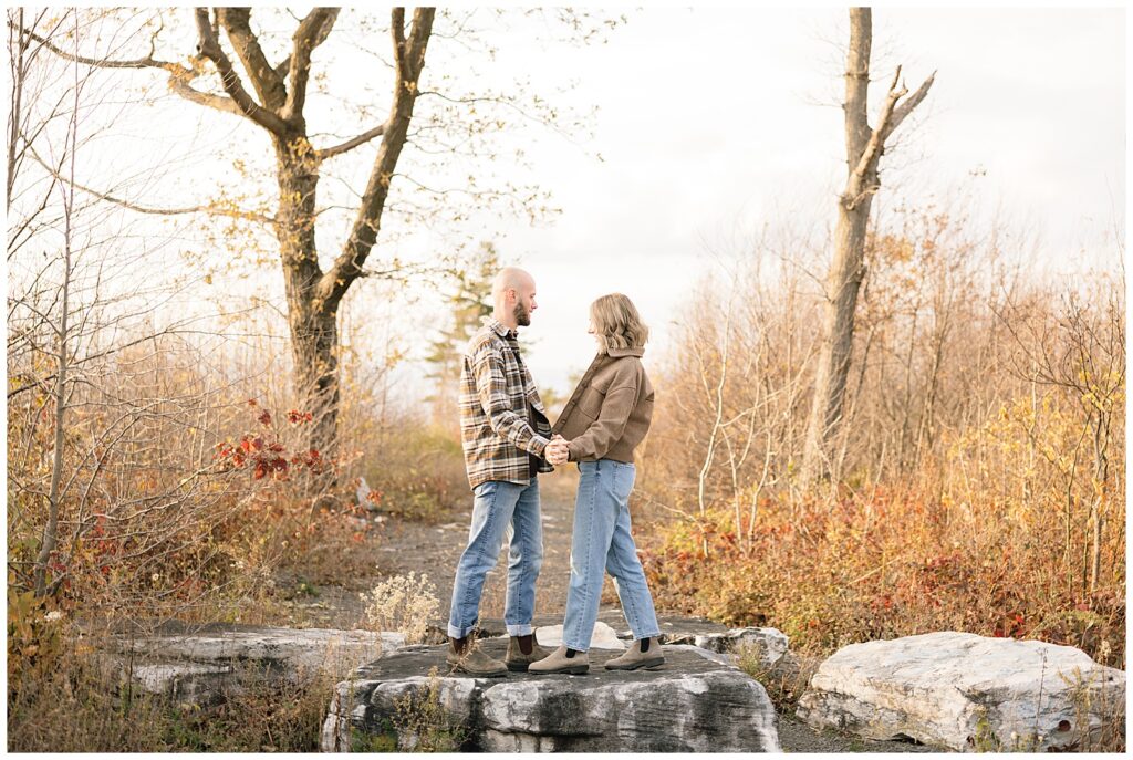 Couple holding hands apart from each other standing on a rock