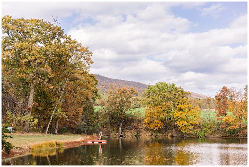 Couple standing on a dock by a pond. 