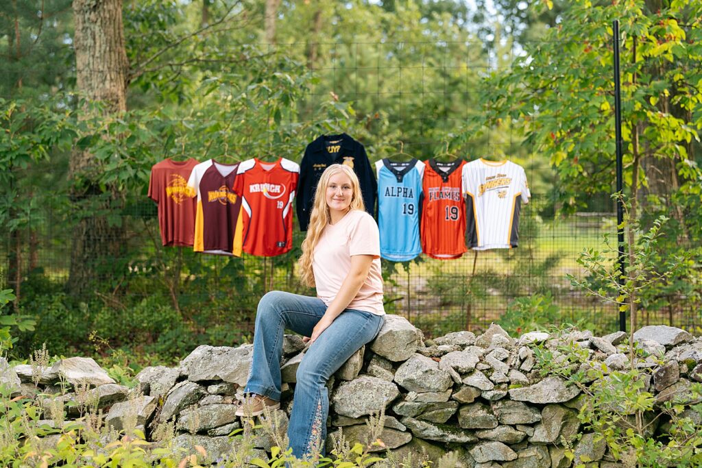 senior girl sitting in front of track jerseys
