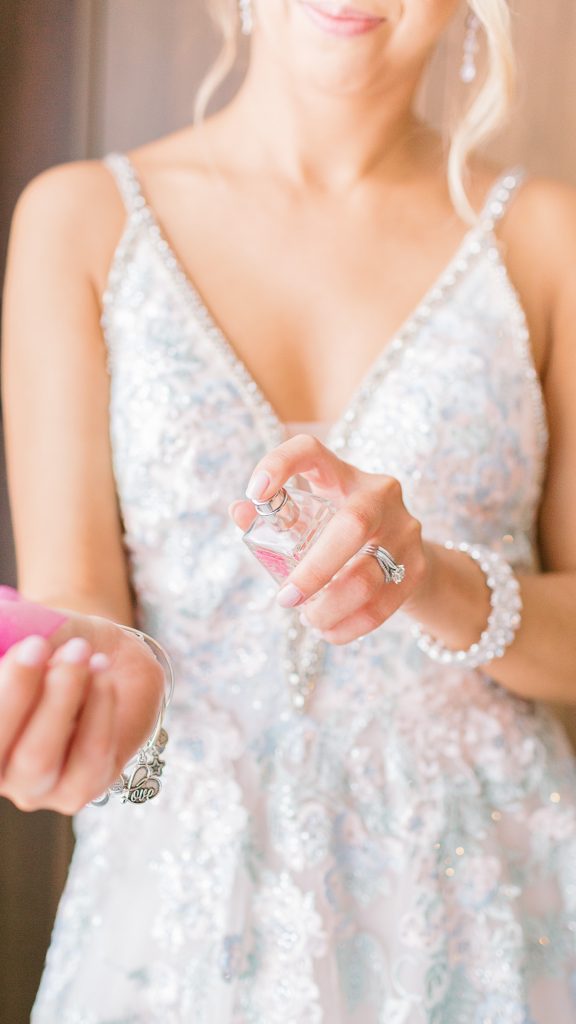 bride spraying her wrist with perfume 