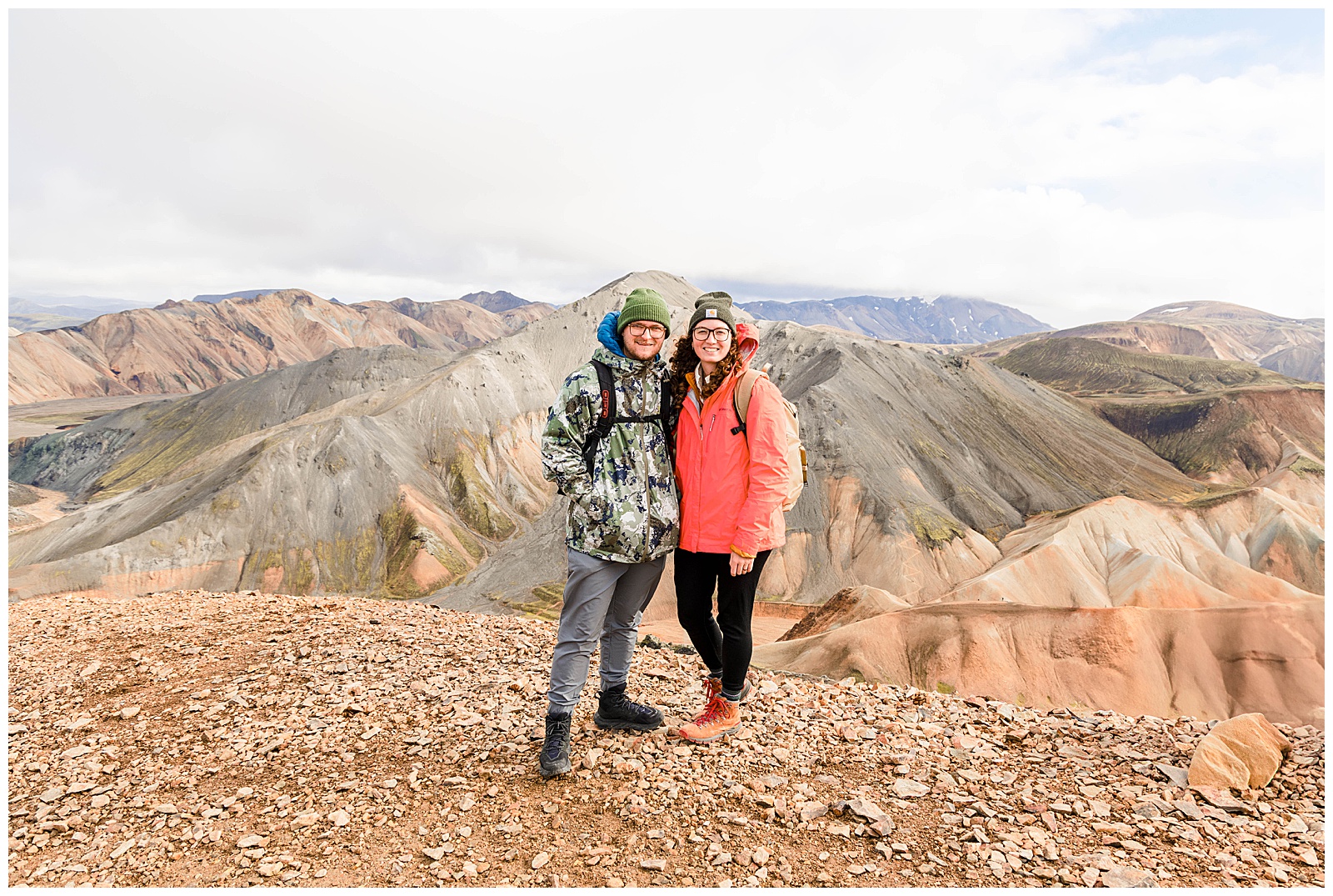 two people standing in front of the rainbow mountains of landmannalaugar