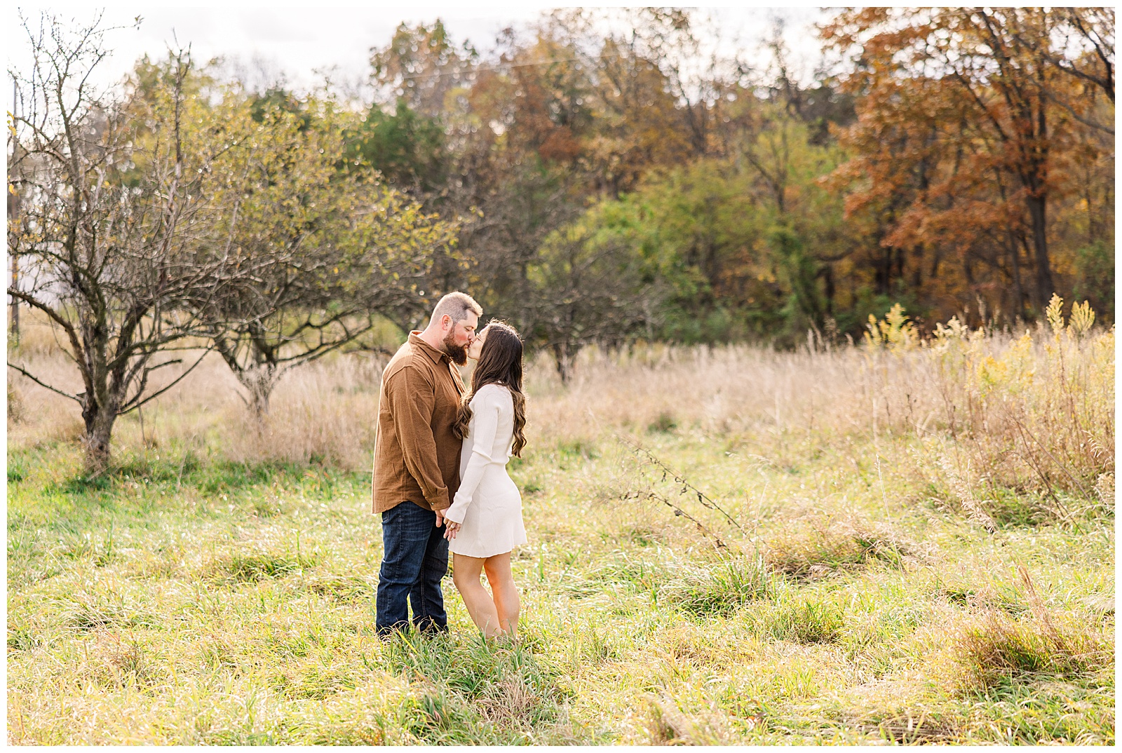 Couple kissing in a field.